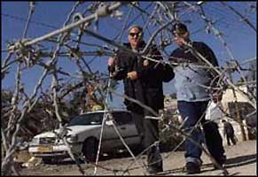 A blind Palestinian is guided past the rolls of barbed wire that make up an impromptu section of the apartheid wall in east Jerusalem.