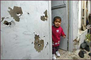 A terrorised child stands in the bullet-ridden doorway of his home in Samarra, after the latest USA raids on the town?s inhabitants leave eight dead.