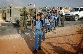Every day the children of Jubara must wait for the soldiers to allow them through the checkpoint, then walk in a line past soldiers armed with machine guns, to go to school.