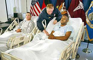 Two young men have the space to contemplate the brutality of their country's war against Iraq. The absurd nationalist regalia hanging behind them fails to provide comfort or dignity.