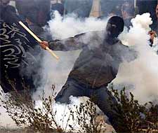 A Palestinian youth throws a tear gas canister back at Israeli soldiers during clashes after Israeli tanks and bulldozers tore up the runway of the Palestinian-controlled international airport in the Gaza Strip.