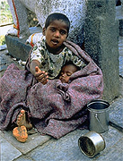 This boy, whose worldly possessions are two mess-cans, asks the photographer to throw him a few coins.