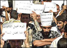 Iraqis demonstrating against the occupation hold paper notices, saying 'Where is the National Government?', and in Arabic, 'Today we carry paper, tomorrow it will be guns.'