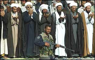 A member of El Imam El Mehdi Army, loyal to Moktada Sadr's group of Shias, guards Friday prayers in Basra. The army gathered on the last Friday of Ramadan to protest against the USA and Israel.